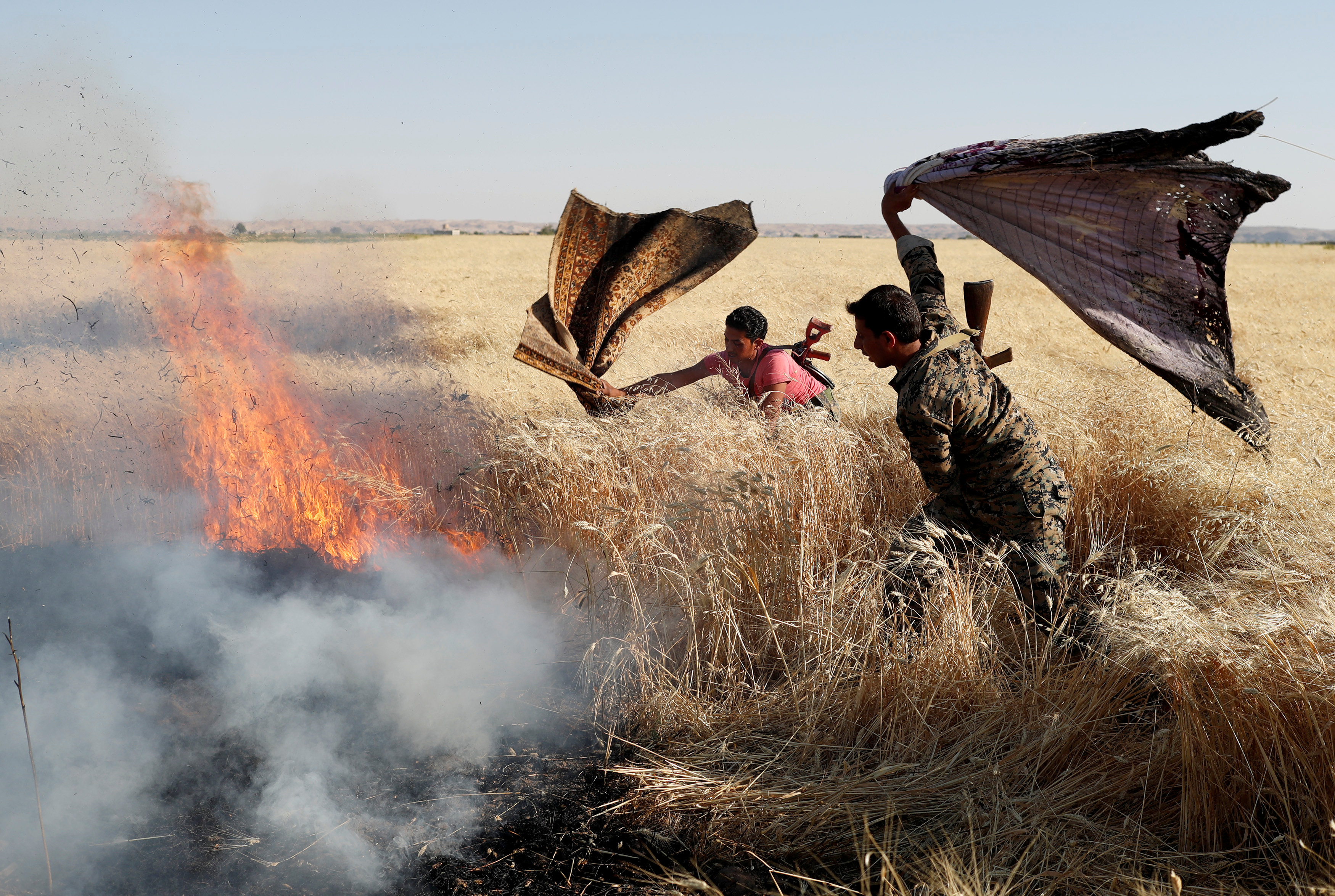 Kurdish fighters extinguishing fire in a wheat field after clashes with ISIS - December 1, 2017 (Reuters)