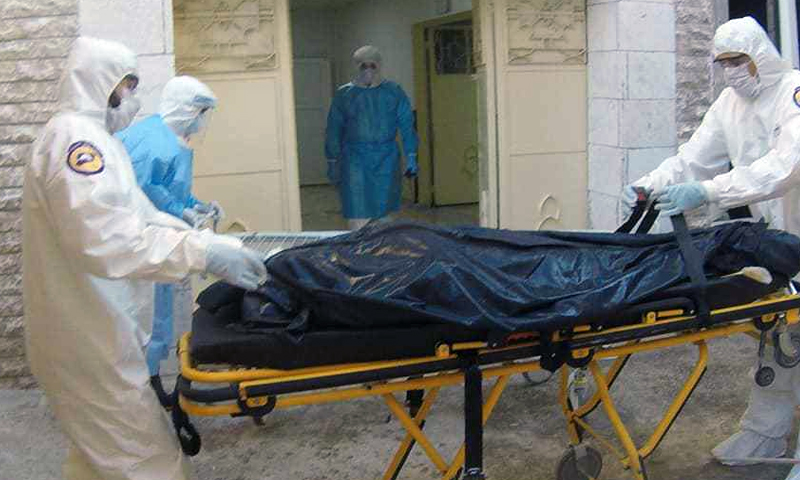 Syrian Civil Defence volunteers in full protective suits and masks carrying the body of a deceased person with COVID-19 infection 16 October 2020 (Syrian Civil Defence)
