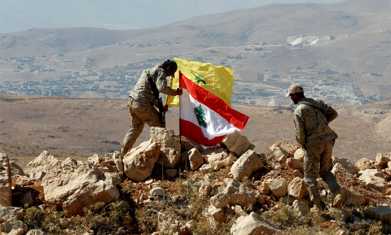 Fighters placing the Lebanese flag next to Hezbolla's flag in Jrood Arsal - 25 July 2017 (Reuters)